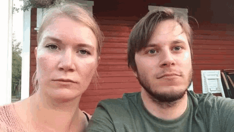 a man and a woman are standing next to each other in front of a red house .