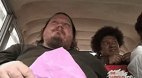a man with a beard is sitting in the back seat of a bus holding a pink piece of paper .