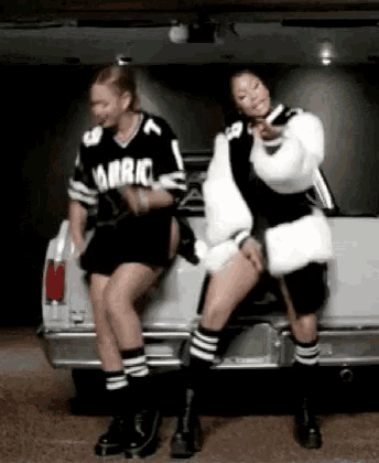 two women are sitting on the back of a car .
