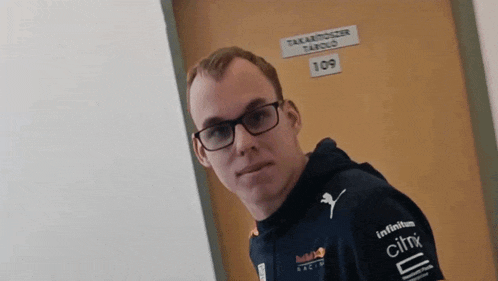 a man wearing glasses and a red bull racing shirt