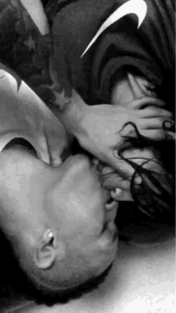 a black and white photo of a man kissing a woman 's feet .