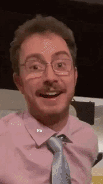 a man wearing glasses and a pink shirt has the word ha on his shirt