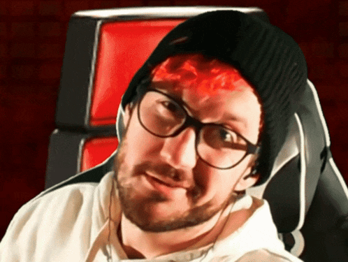 a man wearing glasses and a black beanie is sitting in a chair