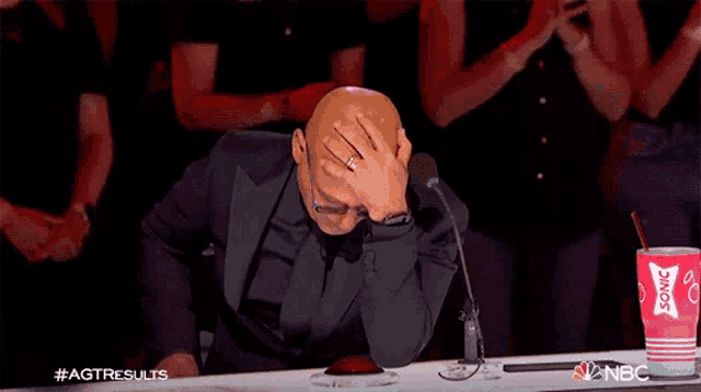 a man is sitting at a table with his hand on his face and a cup of coca cola on it