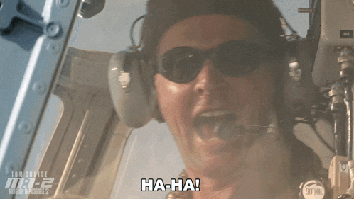 a man wearing headphones and sunglasses says ha-ha in front of a poster for mission impossible 2