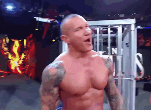 a shirtless wrestler stands in front of a sign that says tna on it