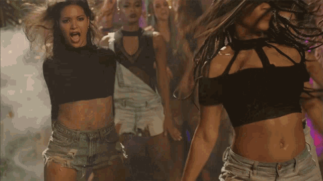 a group of women are dancing and one is wearing a black crop top