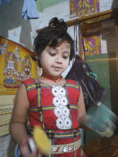 a little girl playing with a toy in front of a wall calendar that says ' a / s rajal '