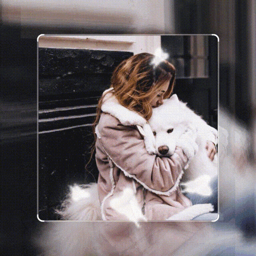 a woman in a pink coat is holding a white dog in her arms