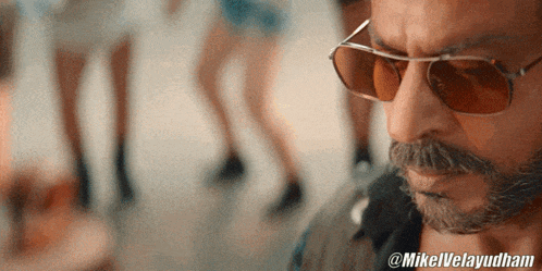 a close up of a man wearing sunglasses and a mustache with @mikelvelayudham written below him