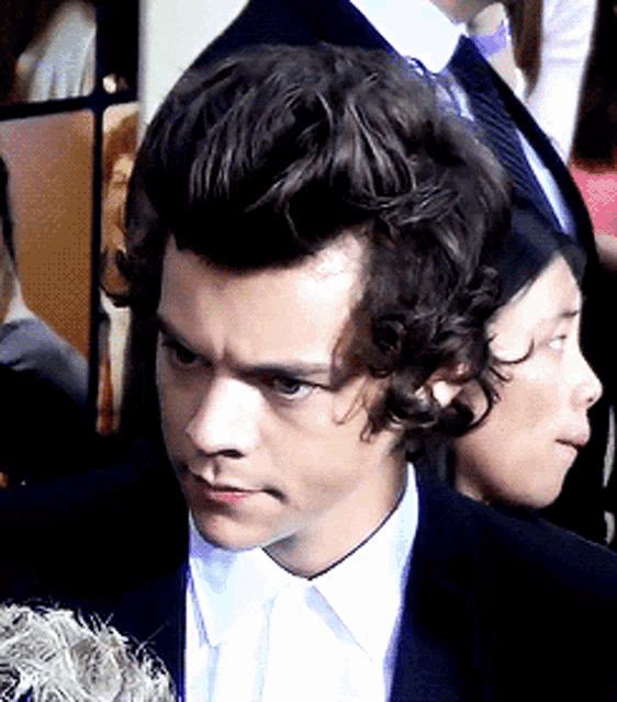 a man with curly hair is wearing a suit and white shirt