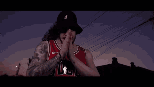 a man wearing a chicago bulls jersey and a black hat