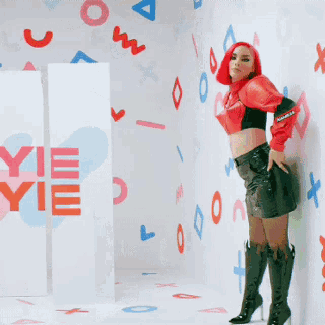 a woman with red hair kisses a man in front of a wall with letters and numbers on it