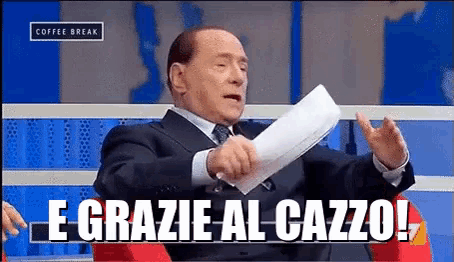 a man in a suit and tie is holding a piece of paper and says e grazie al cazzo !