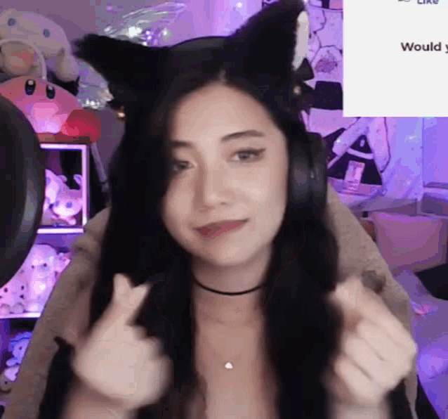 a girl wearing a cat ear headband is giving a thumbs up