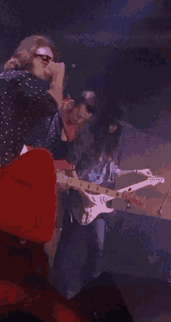 a man is playing a guitar in front of a microphone on stage