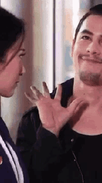 a man and a woman are looking at each other and the woman is touching the man 's neck .
