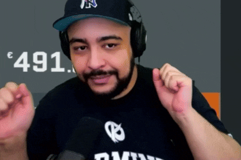 a man wearing headphones and a hat with the letter n on it stands in front of a microphone