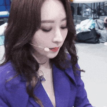 a woman wearing a purple jacket and a microphone