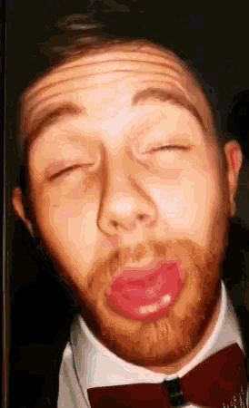 a man with a beard wearing a bow tie making a funny face