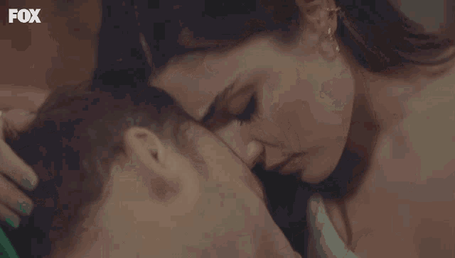 a close up of a woman kissing a man with the fox logo on the bottom