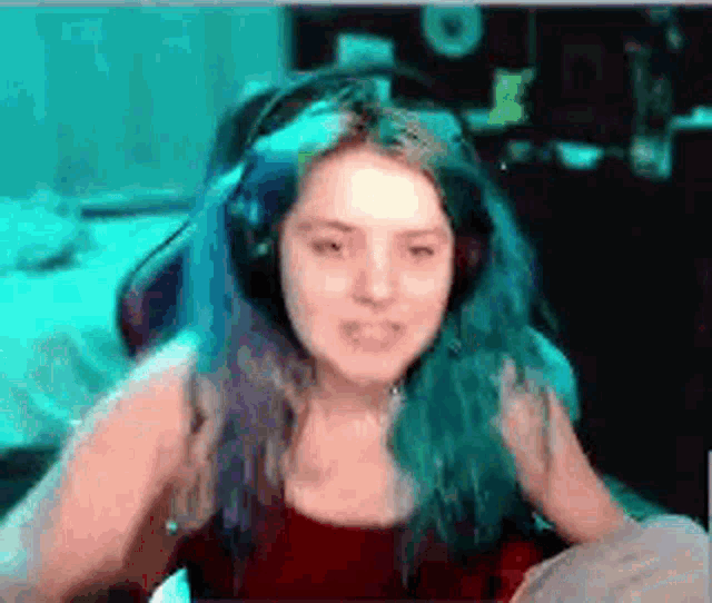 a girl with blue hair is wearing headphones and sitting in a chair .