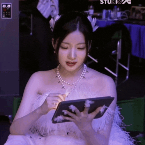 a woman in a white dress is holding a tablet in her hands