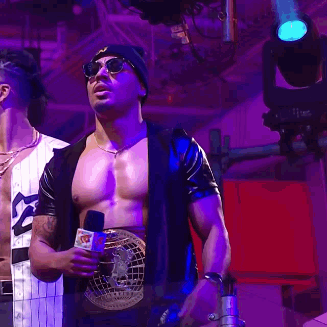 a shirtless man holding a microphone with a belt around his waist that says ' wwe ' on it