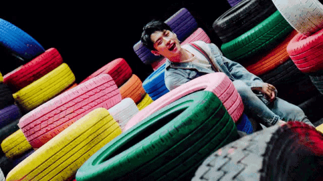 a man is sitting in a pile of colorful tires ..