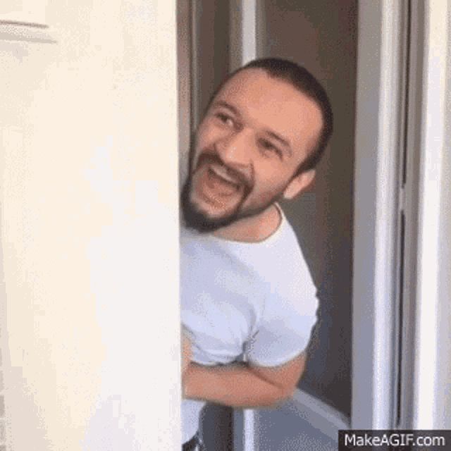 a man with a beard is standing in a doorway laughing .