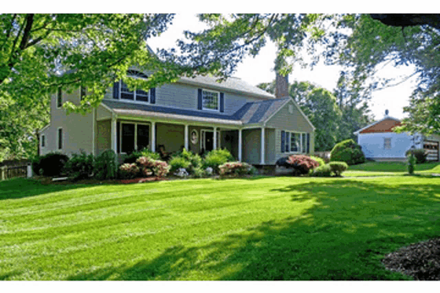 a house with a lush green lawn and trees in front of it