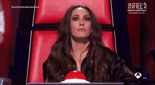 a woman sitting in a red chair with a red button in front of her that says infiel