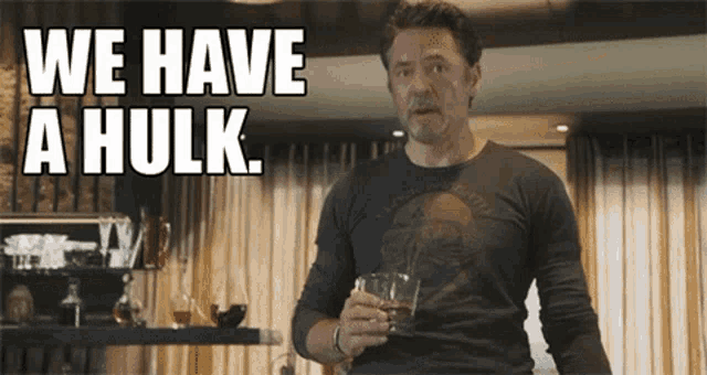 a man is holding a glass of whiskey and saying we have a hulk .