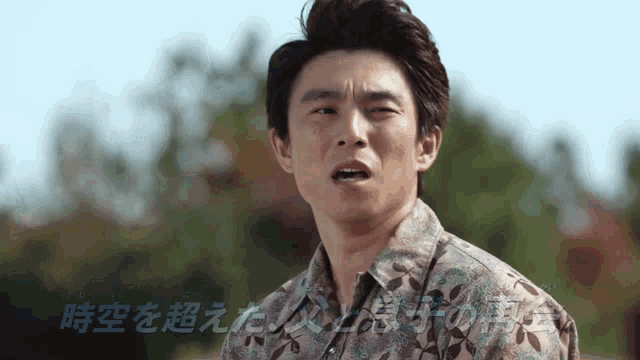 a man in a floral shirt is making a funny face in front of a foreign language text