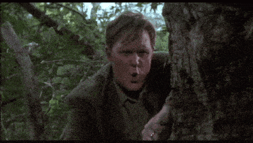 a man with a ring on his finger is standing in the woods