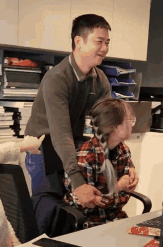 a man in a plaid shirt is hugging a woman