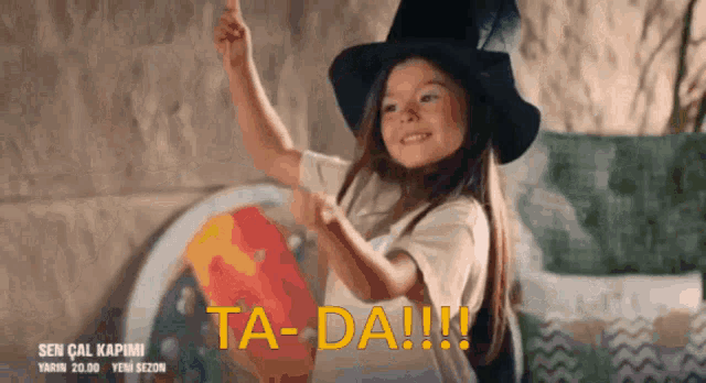 a little girl wearing a witch hat says ta-da-!!!