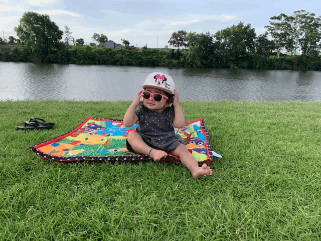 a baby wearing a minnie mouse hat and sunglasses sits on a blanket
