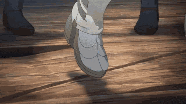 a close up of a person 's foot walking on a wooden surface