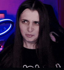a woman with long hair is making a funny face while sitting in a chair in front of a ring light .
