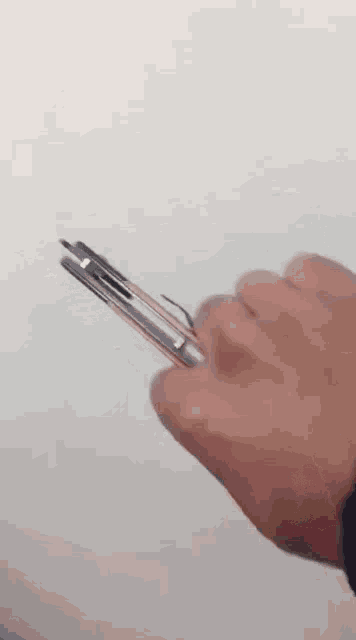 a person is holding a pen in their left hand against a white wall .