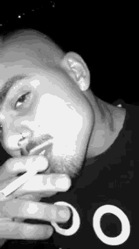 the man is smoking a cigarette in a black and white photo .