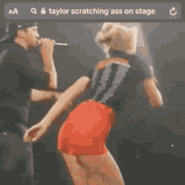 taylor swift is scratching her ass on stage while a man watches .