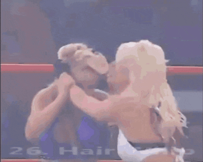 a woman is laying on the ground in a wrestling ring while a man stands behind her
