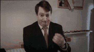 a man in a suit and tie is making a funny face while sitting at a table .