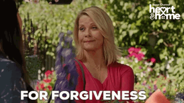 a woman in a pink shirt is talking to another woman in a garden and says for forgiveness .