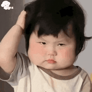 a baby girl is scratching her head with her hand .