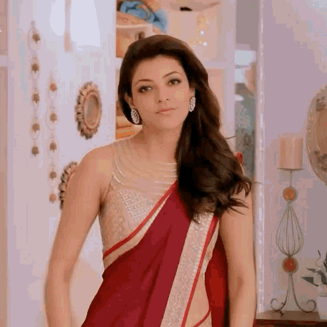 a woman in a red saree is standing in a room