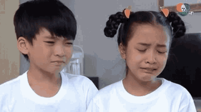 a boy and a girl are standing next to each other . the girl is crying and the boy is laughing .