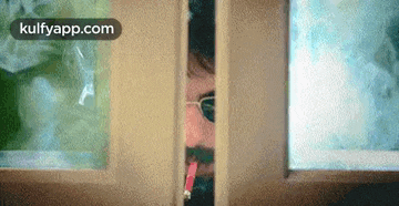 a man is smoking a cigarette while peeking through a door .